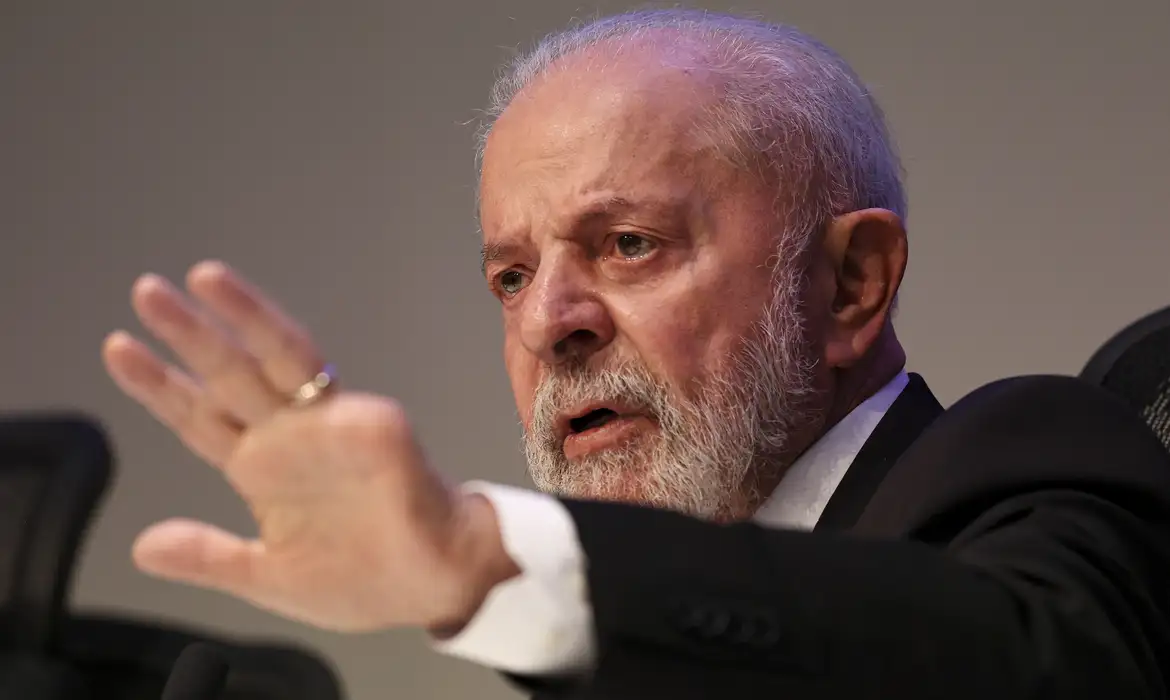 Lula falando e apontando pra frente, sério, sem olhar para a câmera