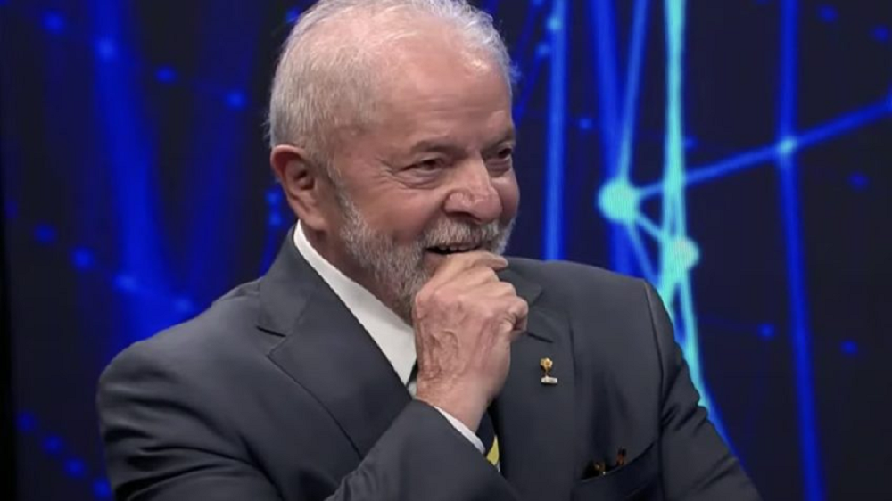 presidente Luiz Inácio Lula da Silva (PT) com a mão no queixo, sorrindo, sem olhar para a câmera