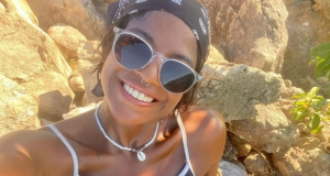 publicitária Juliana Marins de óculos escuros e bandana, olhando para a câmera, sorrindo
