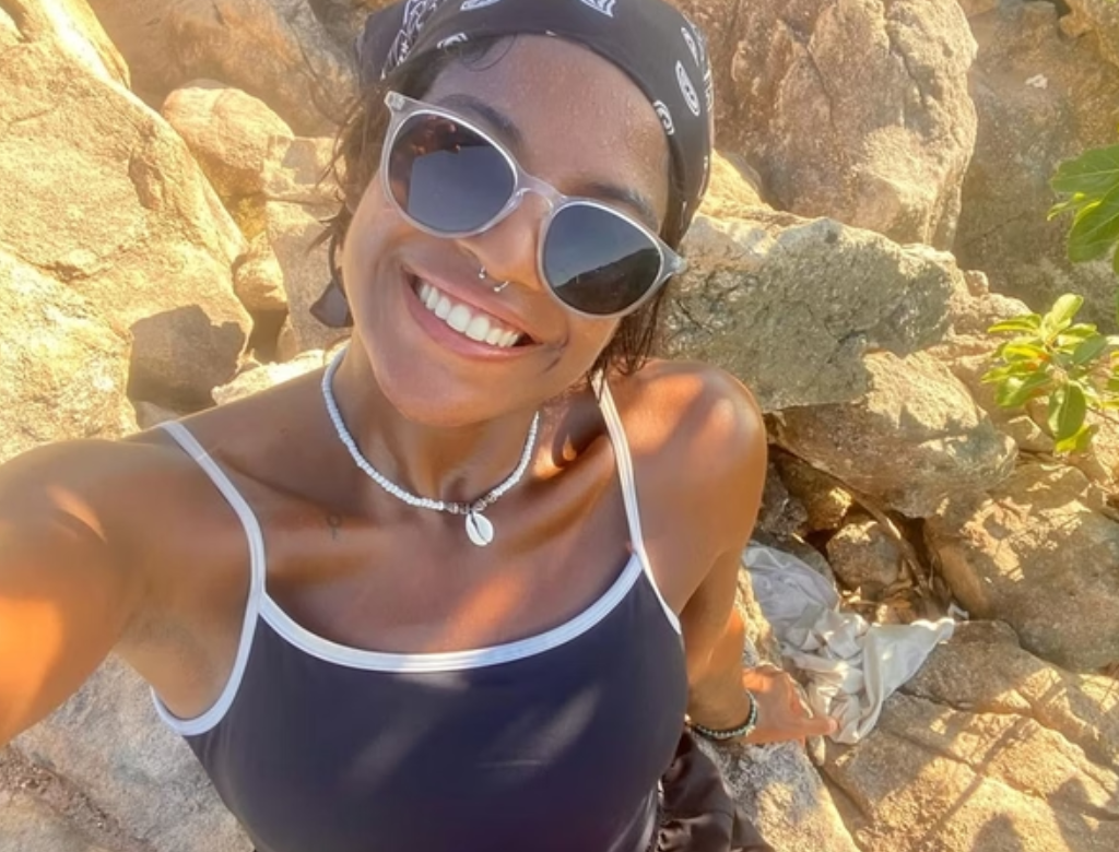 publicitária Juliana Marins de óculos escuros e bandana, olhando para a câmera, sorrindo