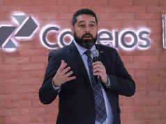 O presidente dos Correios, Fabiano Silva dos Santos, falando em microfone, sério