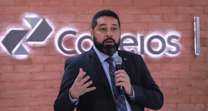 O presidente dos Correios, Fabiano Silva dos Santos, falando em microfone, sério