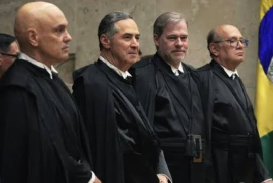 Ministros do STF lado a lado, em pé, sem olhar para a câmera
