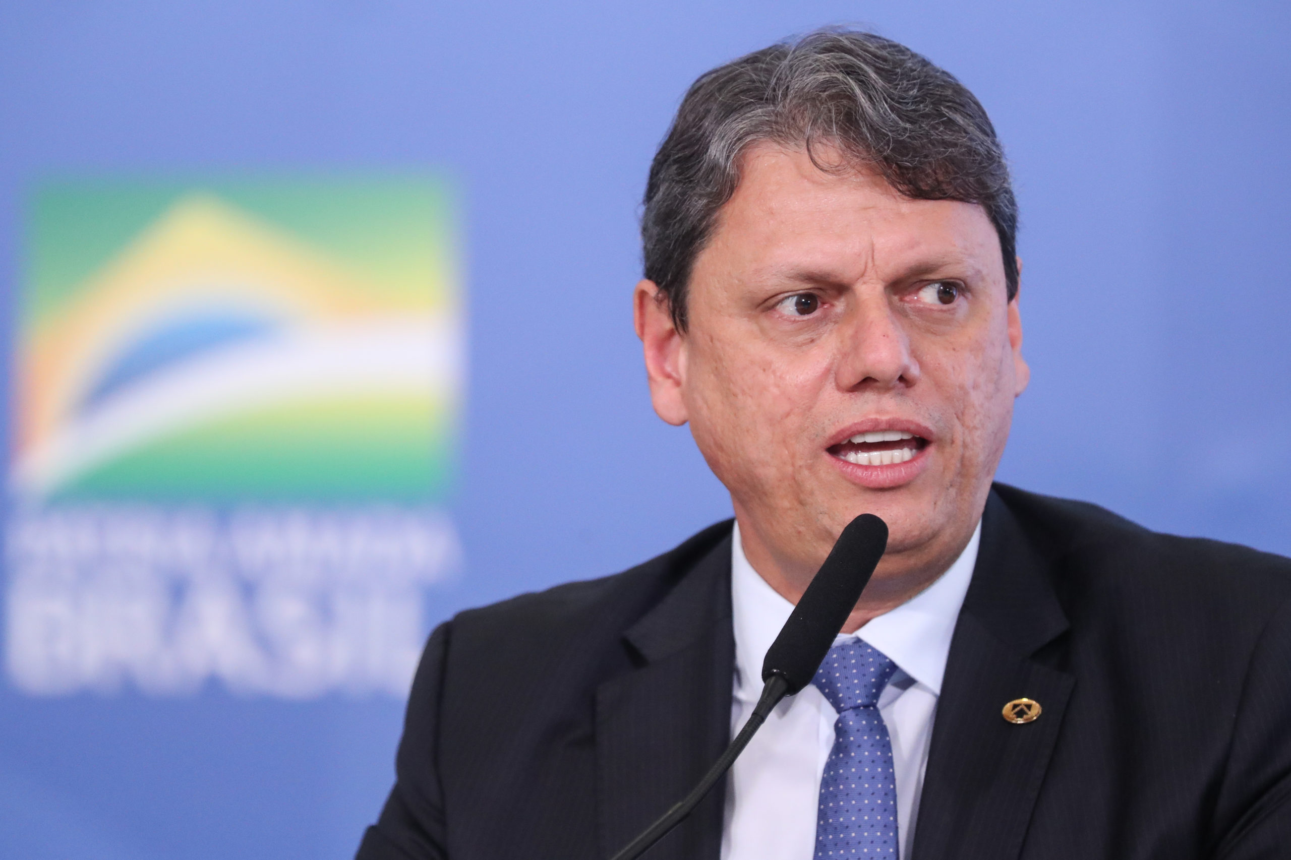 governador de São Paulo, Tarcísio de Freitas, falando em microfone e olhando para o lado, sério