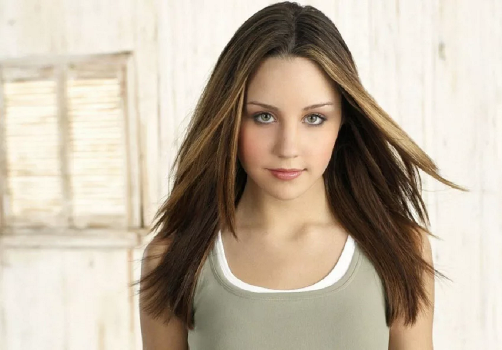 Amanda Bynes ainda na adolescência, de camiseta cinza, posando para foto