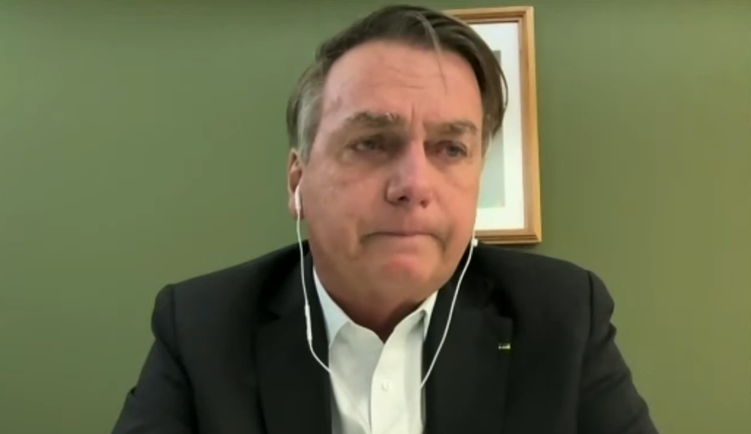 Jair Bolsonaro chorando, de fones de ouvido com fio brancos e roupa social