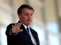 Jair Bolsonaro (PL) sorrindo e acenando