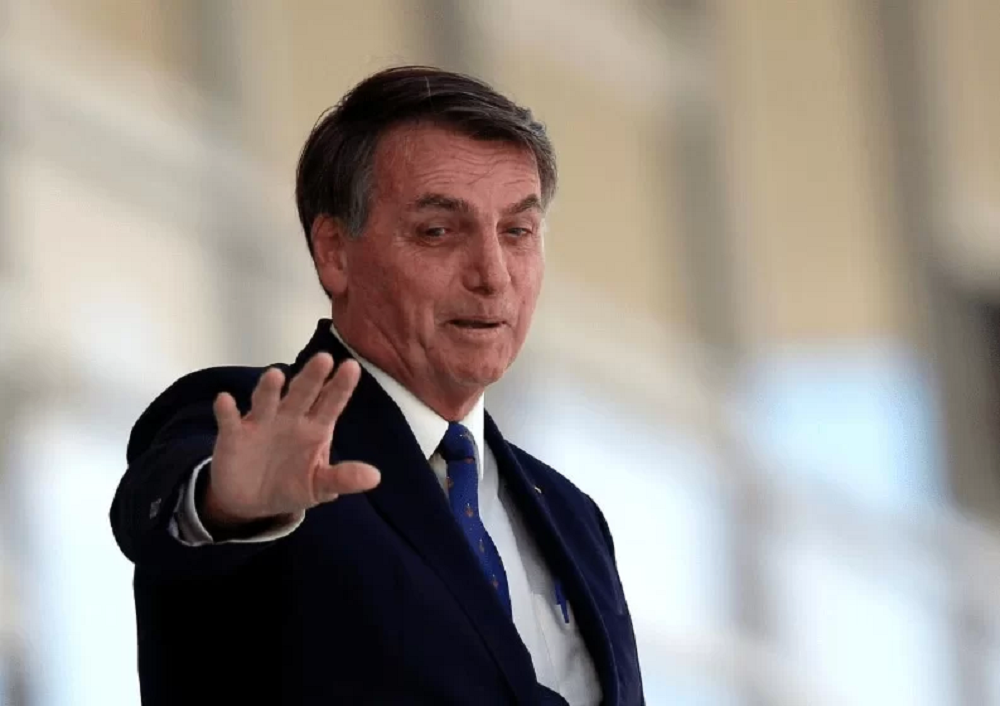 Jair Bolsonaro (PL) sorrindo e acenando