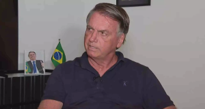 ex-presidente Jair Bolsonaro (PL) olhando para o lado, sério, de camisa azul marinho polo