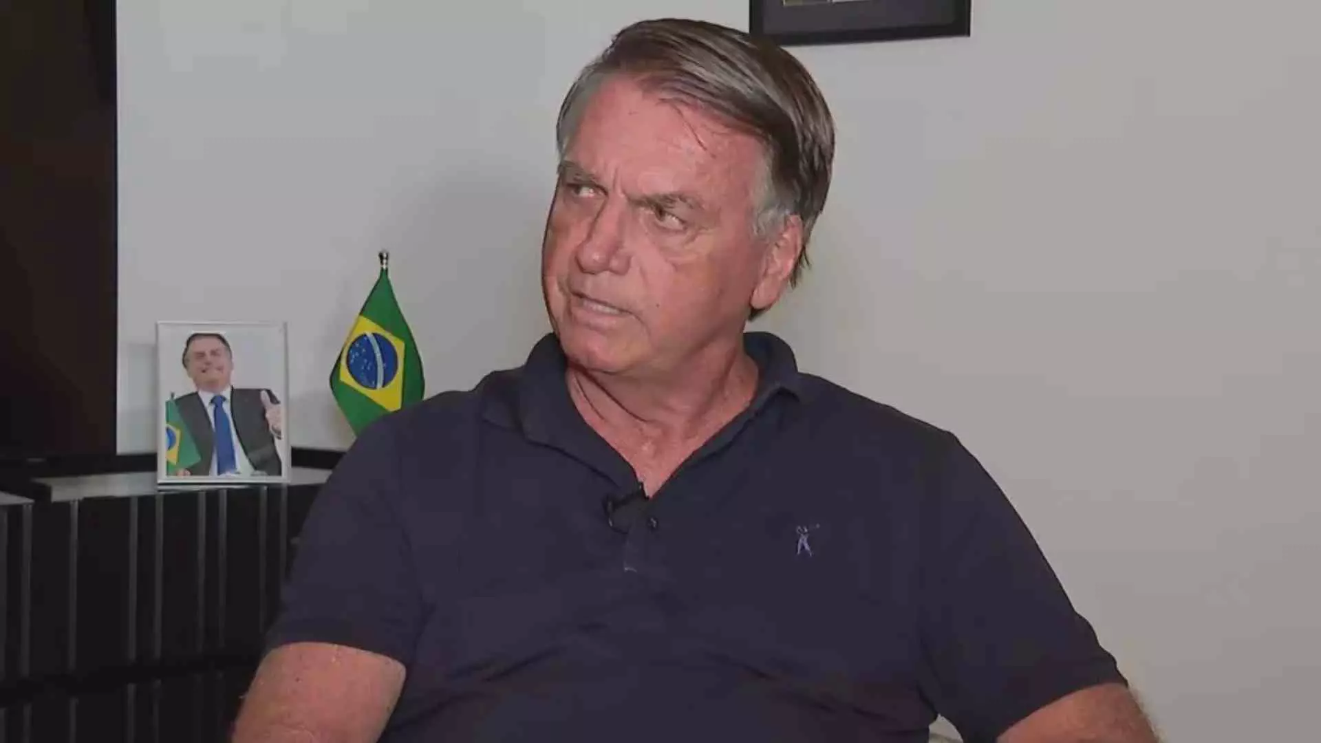 ex-presidente Jair Bolsonaro (PL) olhando para o lado, sério, de camisa azul marinho polo