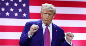O presidente dos Estados Unidos, Donald Trump, gesticulando, sério, na frente de bandeira dos EUA