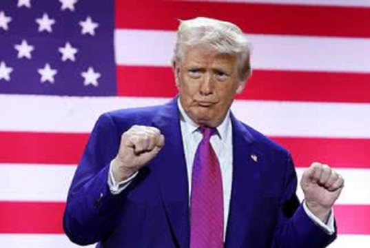 O presidente dos Estados Unidos, Donald Trump, gesticulando, sério, na frente de bandeira dos EUA