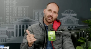 O deputado federal Eduardo Bolsonaro (PL-SP) falando em microfone e gesticulando para a câmera