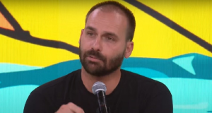 O deputado licenciado Eduardo Bolsonaro falando, sério, de roupa preta