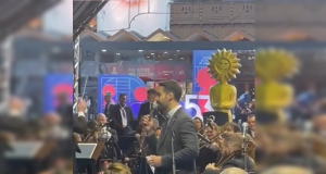 O governador do Rio Grande do Sul, Eduardo Leite (PSD) cantando no centro de montagem, cercado de pessoas