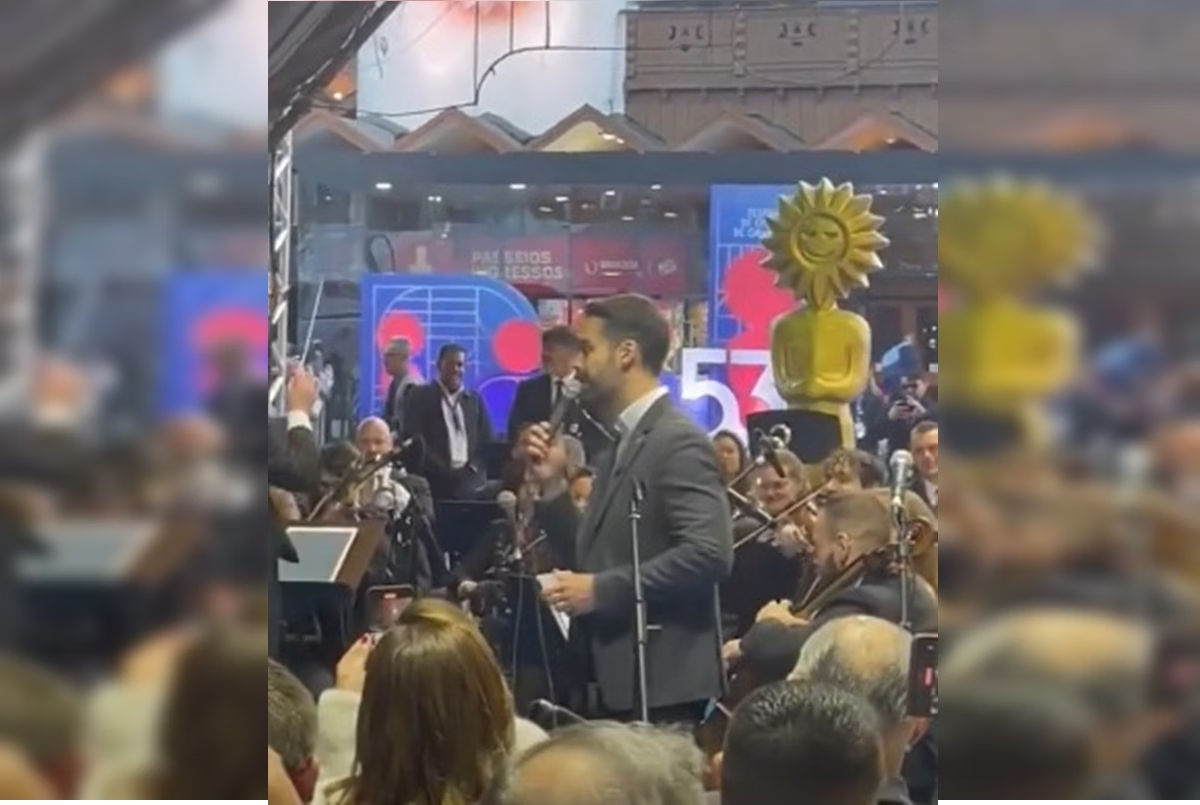 O governador do Rio Grande do Sul, Eduardo Leite (PSD) cantando no centro de montagem, cercado de pessoas