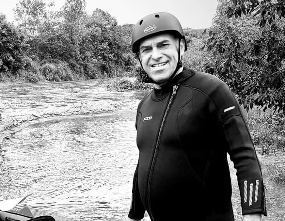 O ex-prefeito de Quebrangulo Marcelo Lima em foto em preto e branco, sorrindo, com roupa de banho e capacete