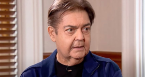 O apresentador Faustão olhando para o lado e falando, sério, de roupa de frio escura
