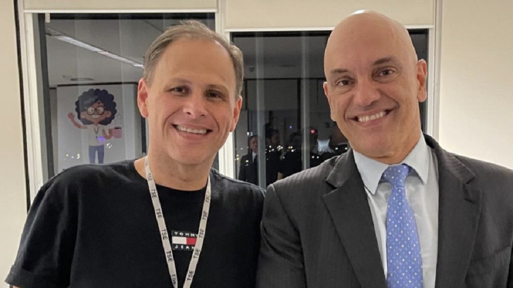 Eduardo Tagliaferro e o ministro Alexandre de Moraes sorrindo lado a lado e olhando para a câmera
