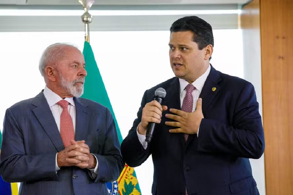 Lula e Davi Alcolumbre em pé, lado a lado, o segundo falando em microfone