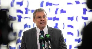 Lindbergh Farias falando em microfones, sério, olhando para o lado