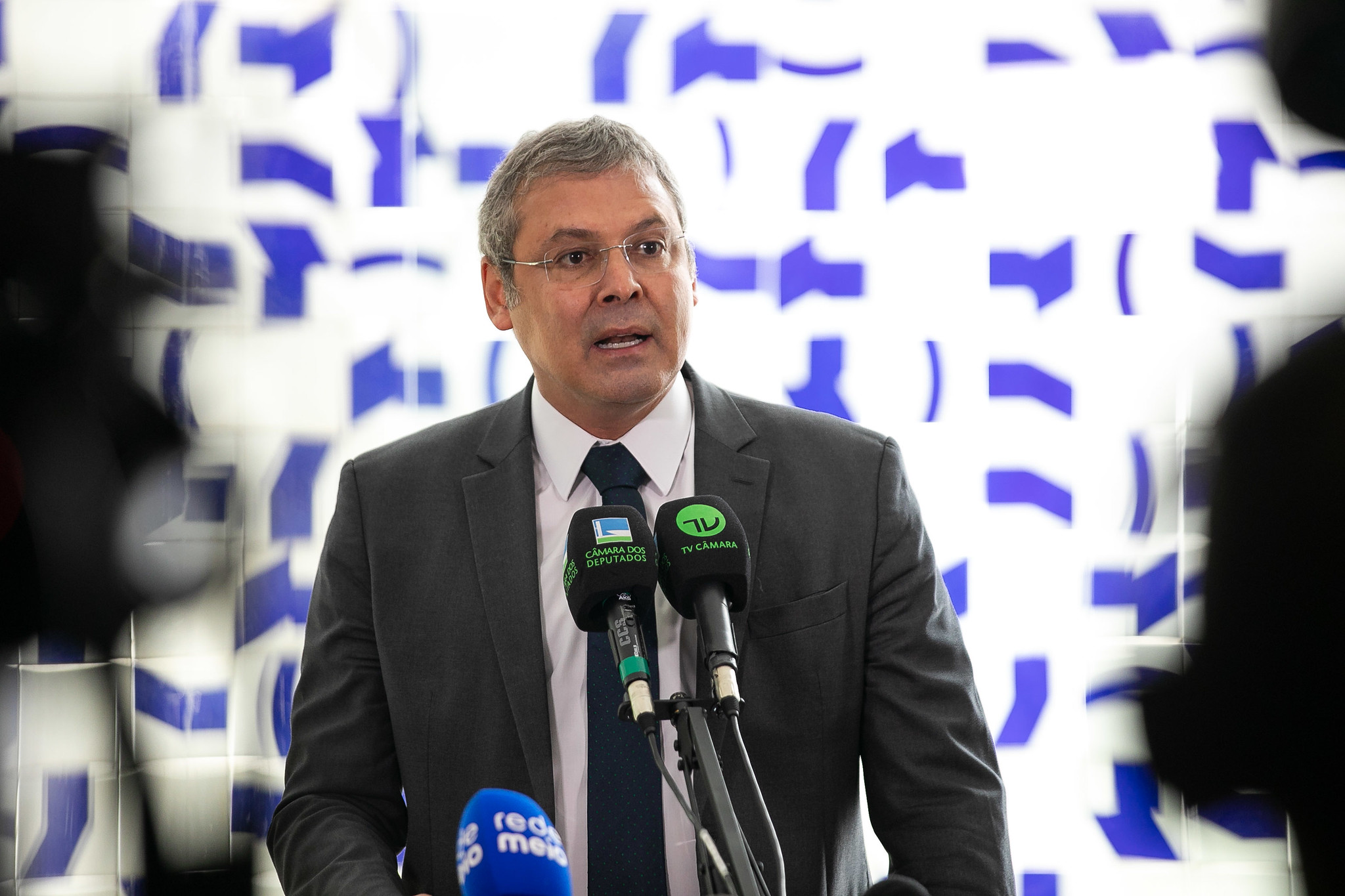 Lindbergh Farias falando em microfones, sério, olhando para o lado