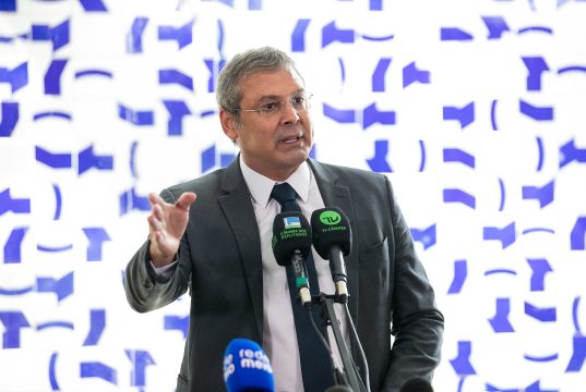 O líder do PT na Câmara dos Deputados, Lindbergh Farias (RJ), em pé, falando em microfone e gesticulando, sério, sem olhar para a câmera, de óculos