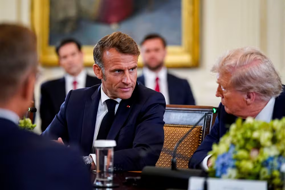 O presidente da França, Emmanuel Macron, e o presidente dos Estados Unidos, Donald Trump conversando sentados à mesa, sérios, lado a lado