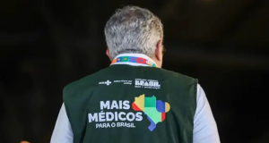 O ministro da Saúde, Alexandre Padilha, de costas com o colete do Mais Médicos