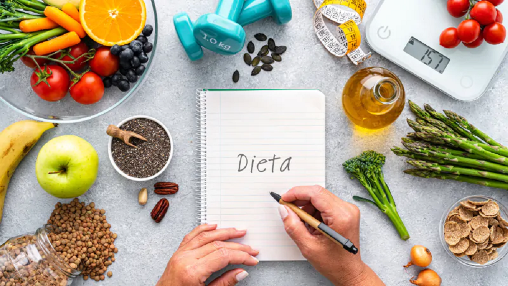 Balança, alimentos e folha com a palavra "dieta" escrita