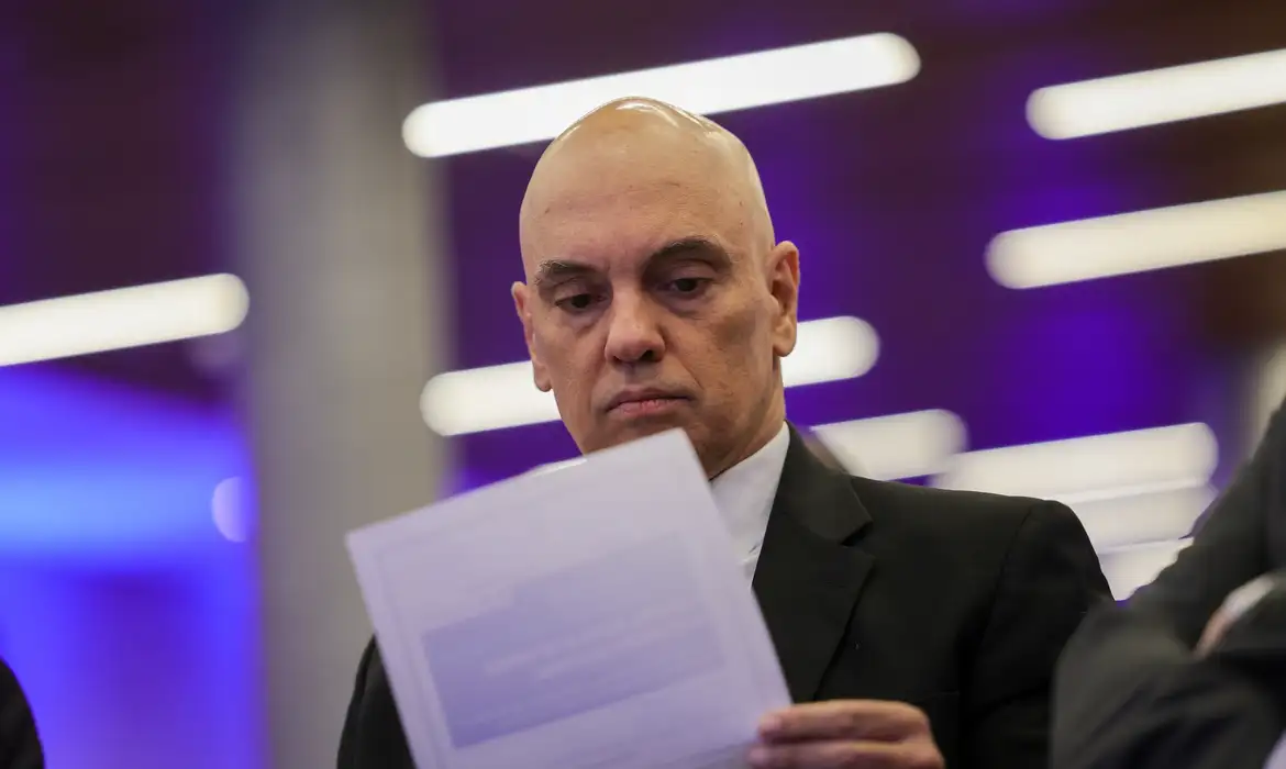 ministro Alexandre de Moraes sério, lendo folha de papel