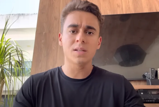 deputado federal Nikolas Ferreira (PL-MG) de camiseta preta, olhando para a câmera com expressão confusa