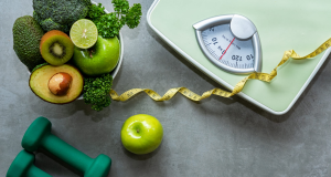 Imagem contendo fita métrica, verduras e legumes, pesos de academia e balança