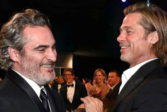 Joaquin Phoenix e Brad Pitt rindo sem olhar para a câmera