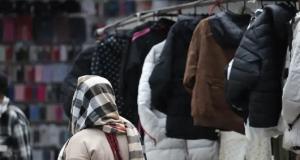 Mulher caminhando de costas com roupa de frio e casacos expostos