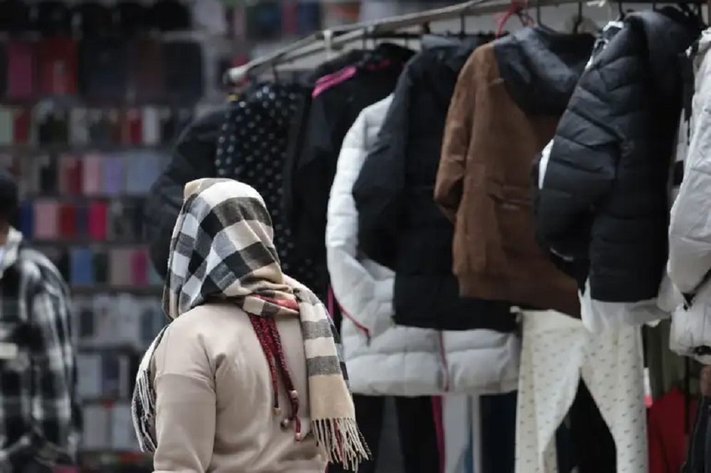 Mulher caminhando de costas com roupa de frio e casacos expostos