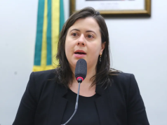 A deputada Sâmia Bomfim (PSOL-SP) de cabelo solto, séria, falando em microfone, de roupa preta, sem olhar para a câmera