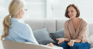 Mulheres conversando em consultório, uma de costas para a câmera