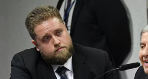 O advogado Matheus Milanez sério, sem olhar para a câmera