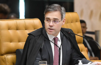 O ministro André Mendonça de óculos, olhando para o lado, sério