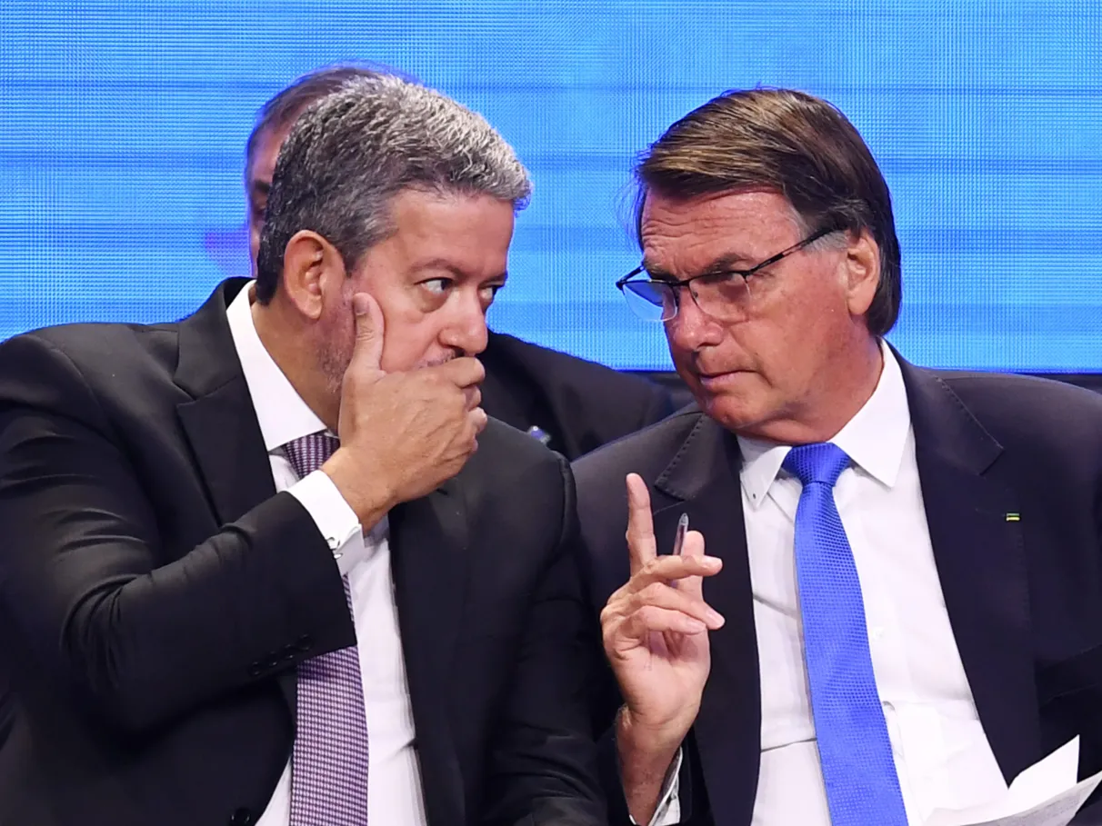 Arthur Lira (PP-AL) e o ex-presidente Jair Bolsonaro (PL) conversando, sérios, sentados lado a lado