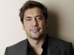 Javier Bardem olhando para a câmera sem sorrir, de roupa social escura, em close