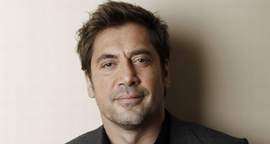 Javier Bardem olhando para a câmera sem sorrir, de roupa social escura, em close