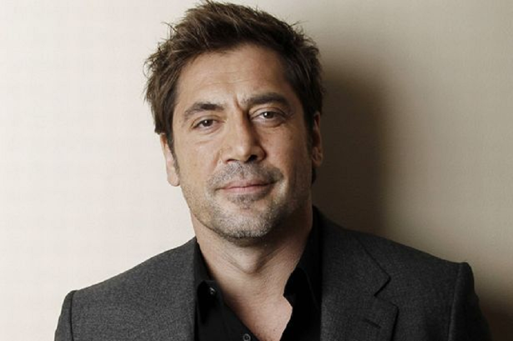 Javier Bardem olhando para a câmera sem sorrir, de roupa social escura, em close