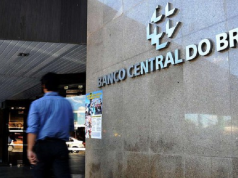Homem desfocado andando na frente do prédio do Banco Central (BC)