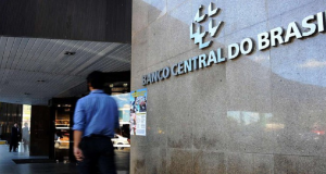 Homem desfocado andando na frente do prédio do Banco Central (BC)