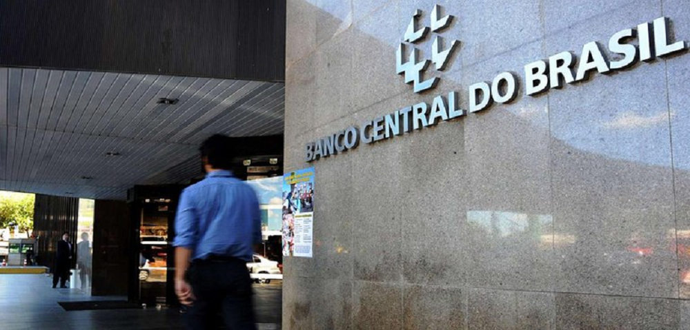 Homem desfocado andando na frente do prédio do Banco Central (BC)