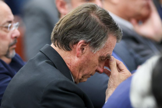 ex-presidente Jair Bolsonaro (PL) de cabeça baixa, sério, com a mão no rosto
