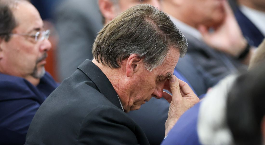 ex-presidente Jair Bolsonaro (PL) de cabeça baixa, sério, com a mão no rosto