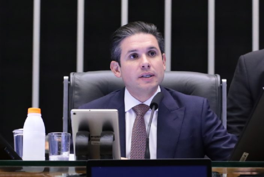 O presidente da Câmara dos Deputados, Hugo Motta, falando e olhando para o lado